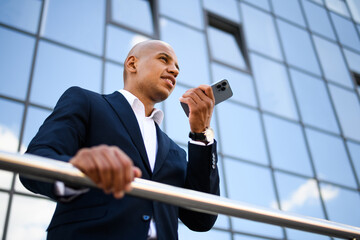 Low angle view of african american businessman recording voice message on smartphone on street 