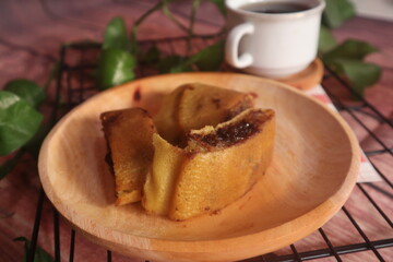 Sweet chocolate flavored martabak served on a wooden plate and accompanied by a glass of warm tea