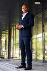 Hairless african american businessman in formal wear looking at camera near office outdoors 