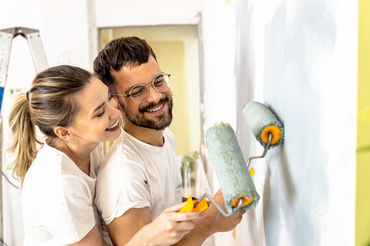 Young couple painting wall in their home.