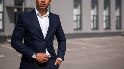 Partial shot of african american businessman in suit standing on street