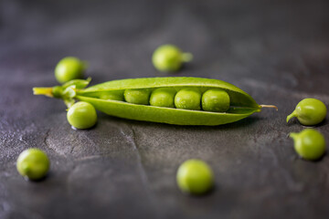 Green pea pod on a black background. Close-up photo of vegetables. 