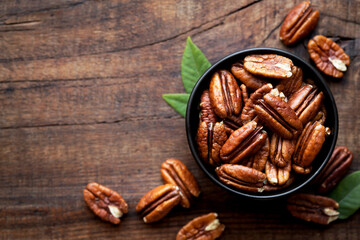 Shelled Pecan nuts in a black bowl against dark rustic background