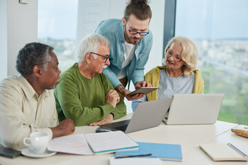 Obraz premium A group of senior students sit in a classroom with their teacher and work on a school project.