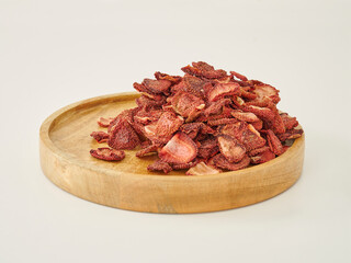 Fresh many strawberry dried fruit on the white background, in the wooden cup.