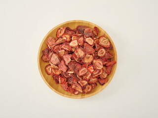 Fresh many strawberry dried fruit on the white background, in the wooden cup.