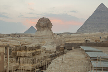 Landscape with Egyptian pyramids, Great Sphinx and silhouettes Ancient symbols and landmarks of Egypt for your travel concep in golden sunlight. The Sphinx in Giza pyramid complex at sunset - obrazy, fototapety, plakaty