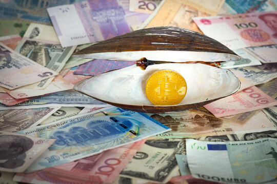 Gold coin of Bitcoin as pearl in an open seashell on background from global currency banknotes