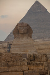 Fototapeta na wymiar Landscape with Egyptian pyramids, Great Sphinx and silhouettes Ancient symbols and landmarks of Egypt for your travel concep in golden sunlight. The Sphinx in Giza pyramid complex at sunset