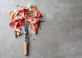 Prosciutto with rosemary on an old concrete background.
