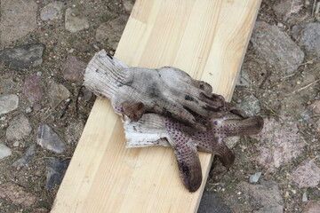 Dirty work gloves pair on a wooden beam. Building construction equipment