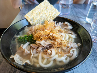 A bowl of hotpot soup with udon noodles, vegetables and tofu