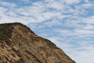 Fototapeta na wymiar A rocky hill on the California coast with blue cloudy skies above