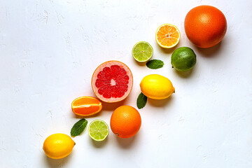 Fresh lemon, orange, grapefruit, lime, green leaves on light background, top view.