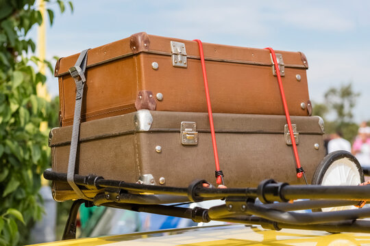 Close-up of old suitcases tied on the trunk of a car against the sky. Travel concept