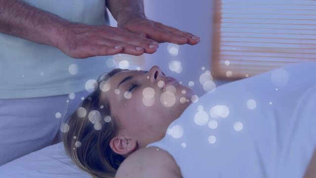 Animation of dots moving over hands of caucasian man doing massage to female customer