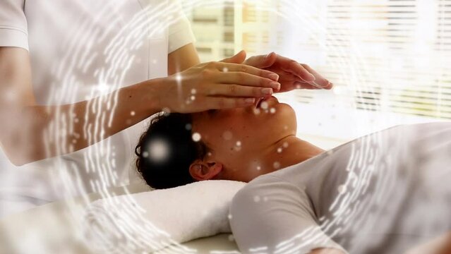 Animation of circles moving over hands of caucasian man doing massage to female customer