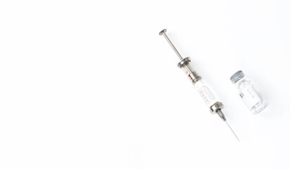 a syringe filled with medicine, next to a jar of medicines on an isolated white background