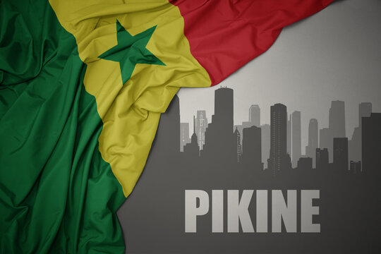 abstract silhouette of the city with text Pikine near waving colorful national flag of senegal on a gray background.