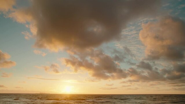 Time lapse with evening landscape of the sunset sky with orange clouds over the sea surface. Picturesque time lapse view sun setting over the sea and dark clouds blowing during sunset over the sea.