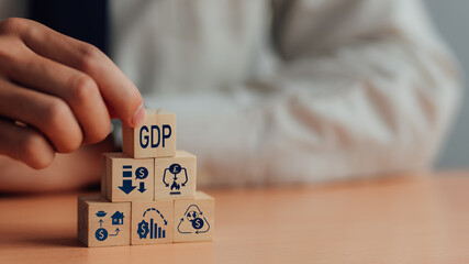 GDP, symbol of gross domestic product Businessman holding a wooden block with an icon saying 'GDP' copy space. Business and GDP growth. Gross domestic product concept.