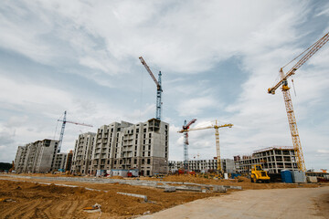 unfinished apartment buildings at the construction site and cranes in background