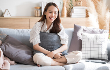 Asian woman happily watch tv comedy series on sofa living room at home