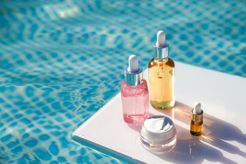 Different packages of cosmetics SPF on background of blue water on sunny summer day