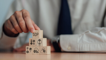 GDP, symbol of gross domestic product Businessman holding a wooden block with an icon saying 'GDP' copy space. Business and GDP growth. Gross domestic product concept.