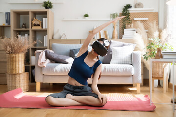 Young Asian female doing yoga in VR glasses at home