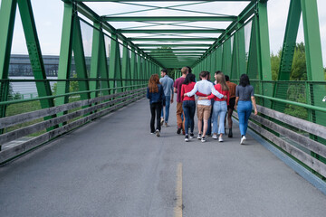 Group of young people crossing a bridge back to back and together