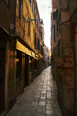 Fototapeta na wymiar Empty dark narrow cobbled street in Venice, Italy