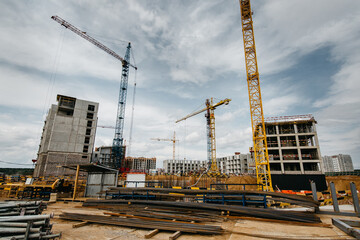 unfinished apartment buildings at the construction site and cranes in background