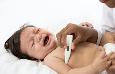 doctor measuring baby's temperature and baby crying on bedroom