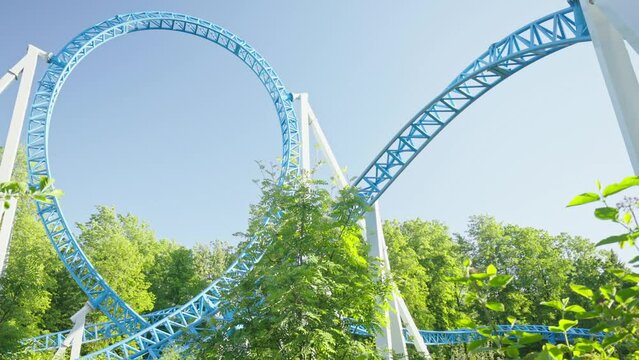 Roller coaster Ride against blue sky. Roller coaster in the amusement park. Cheerful entertainments in park of attractions