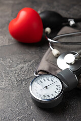 Gray tonometer and heart on a black marble background. Medical equipment blood pressure monitor....