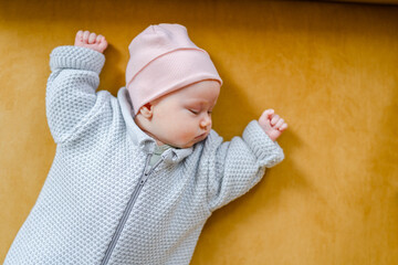 A baby dressed in a warm jumpsuit is getting ready for a walk, a funny kid in a hat