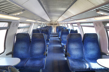 Empty cabin of a modern passenger train. Empty blue seats inside train cabin, corridor view, no...