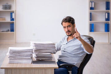 Young male employee unhappy with excessive work in the office