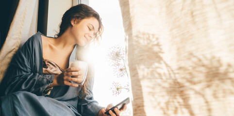 Beautiful woman in blue pajamas drinking coffee at the morning.