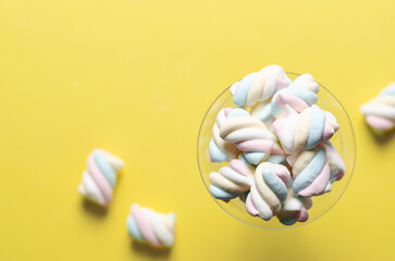 White, yellow, pink, and light blue marshmallows on yellow background with copy space. 