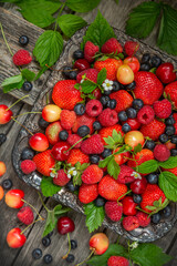 Many different ripe berries strawberries, raspberries, blueberries, cherries, on an old dish and a wooden background. View from above