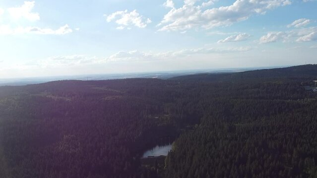drone footage over a forest and a lake with skyline and clouds