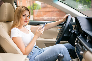young woman is typing text messages on her smartphone while driving a car.