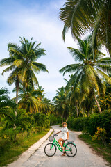 Woman on a old vintage bicycle. Happy young girl riding a bike on a footpath with palm trees at the sea. Leisure and active lifestyle concept