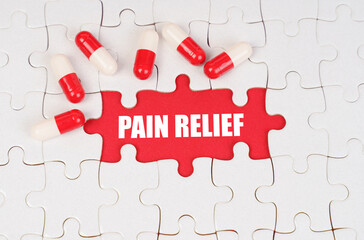 There are pills on the white puzzles, in the middle there is a red surface with the inscription - PAIN RELIEF