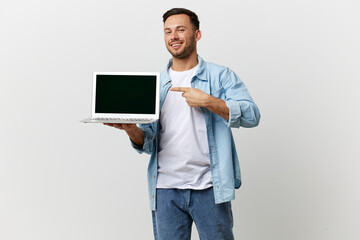 Cheerful friendly tanned handsome IT professional man in casual basic t-shirt point finger at laptop posing isolated on white studio background. Copy space Banner Mockup. Electronics repair concept