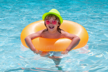 Kid boy playing with inflatable floating ring in swimming pool. Summer vacation concept. Summer kids portrait in sea water on beach.