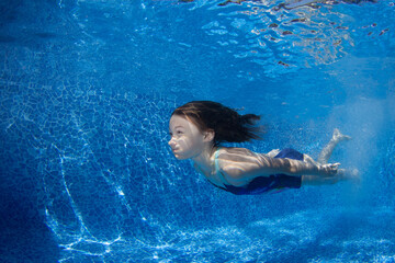 Young girl swims underwater in the pool.