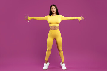 Fototapeta na wymiar Sporty young brunette woman stretching before exercise over purple background. Power and motivation concept.
